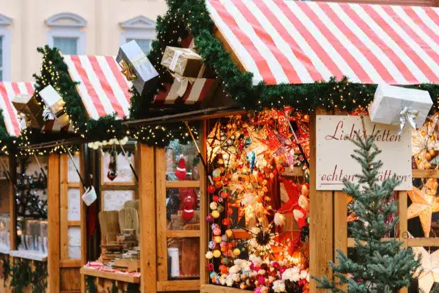Puestos de madera y árbol iluminado en el mercado navideño de la Grote Markt de Brujas